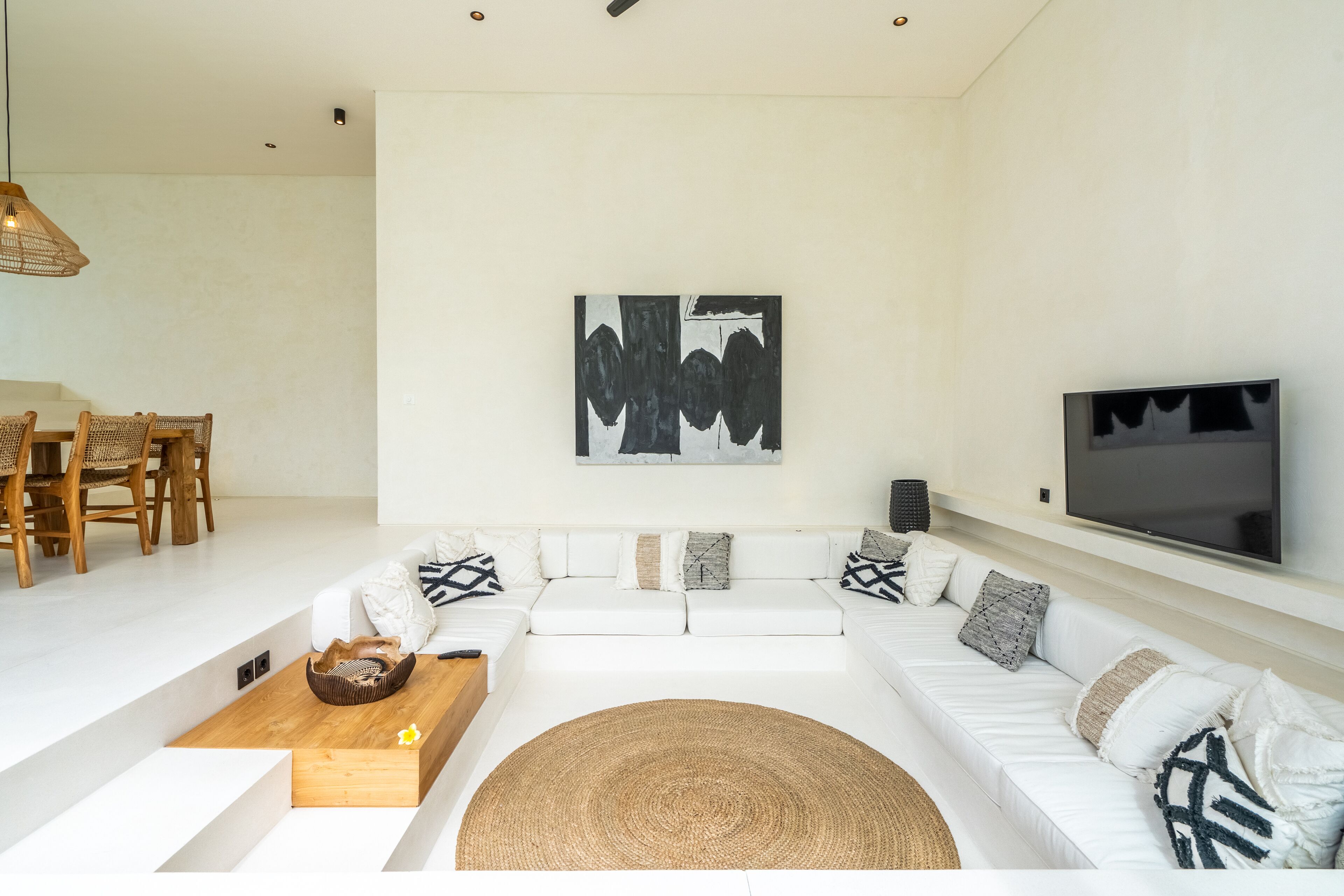 Una sala de estar moderna con un sofá blanco, un televisor de pantalla plana grande y una alfombra tejida.