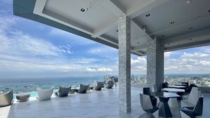 A rooftop terrace with modern seating, a pool, and a view of the sea and city skyline. - Arcadia Millennium Tower by PSR (Pattaya)