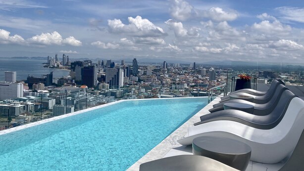 A rooftop infinity pool with a cityscape view, modern lounge chairs, and a potted plant. - Arcadia Millennium Tower by PSR (Pattaya)