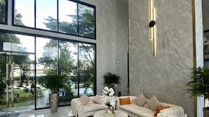 A spacious lobby with a large seating area, a marble floor, and large windows offering a view of the outdoors. - Arcadia Millennium Tower by PSR (Pattaya)
