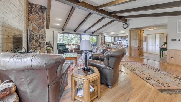 A spacious living room with leather sofas, a coffee table, and a stone wall. - Ruidoso Retreat w/ Sierra Blanca Peak Views! (Ruidoso)