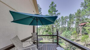 A balcony with a green umbrella, two chairs, and a small table. - Ruidoso Retreat w/ Sierra Blanca Peak Views! (Ruidoso)