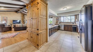 A spacious kitchen with wooden cabinets, a refrigerator, and a dining area with a table and chairs. - Ruidoso Retreat w/ Sierra Blanca Peak Views! (Ruidoso)