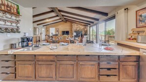 A spacious kitchen with a large island, wooden cabinets, and a stone wall. - Ruidoso Retreat w/ Sierra Blanca Peak Views! (Ruidoso)