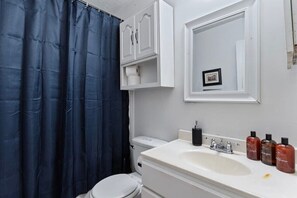 Et badeværelse med en hvid vask, et spejl og toiletartikler.