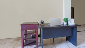 A desk with a laptop, a fan, and a small potted plant. - OYO 92512 Atlanta Guesthouse (Semarang)