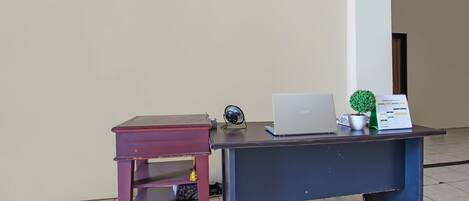 Et skrivebord med en bærbar computer, en ventilator og en lille potteplante.