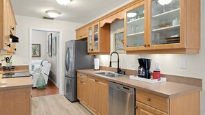 A modern kitchen with wooden cabinets, stainless steel appliances, and a dishwasher. - Palm Paradise- Charming Island Bungalow in Downtown Sanibel (Sanibel)