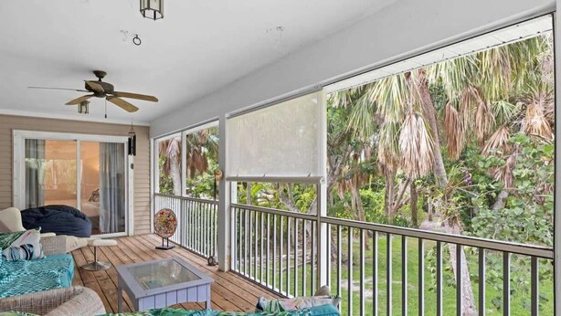 A covered balcony with a ceiling fan, a glass table, and a sofa with tropical cushions. - Palm Paradise- Charming Island Bungalow in Downtown Sanibel (Sanibel)