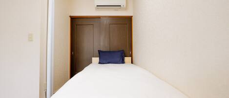 Une chambre avec un lit, une armoire en bois et un climatiseur fixé au mur.