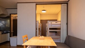 A compact living space with a kitchenette, a dining area with a wooden table and chairs, and a sofa. - Furano Zone Ski Condo (Furano)