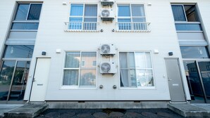A two-story building with multiple air conditioning units mounted on the exterior walls. - Furano Zone Ski Condo (Furano)