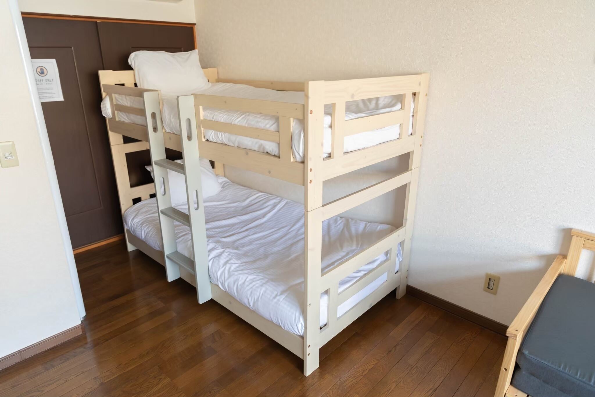 A bunk bed room with a wooden floor and a door with a sign.