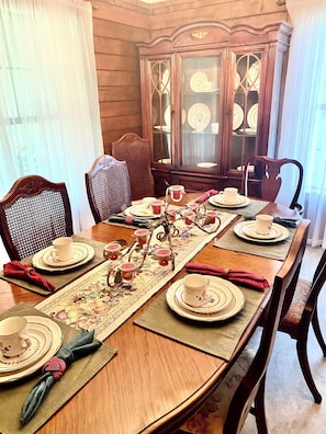 Une table à manger dressée avec des assiettes, des tasses et un centre de table décoratif.