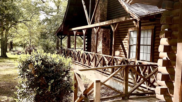 A rustic wooden cabin with a covered porch and a stone foundation. - Cozy Country Home 3BR 3BA, 3200 sq. ft. will make your stay truly unforgettable! (Lufkin)