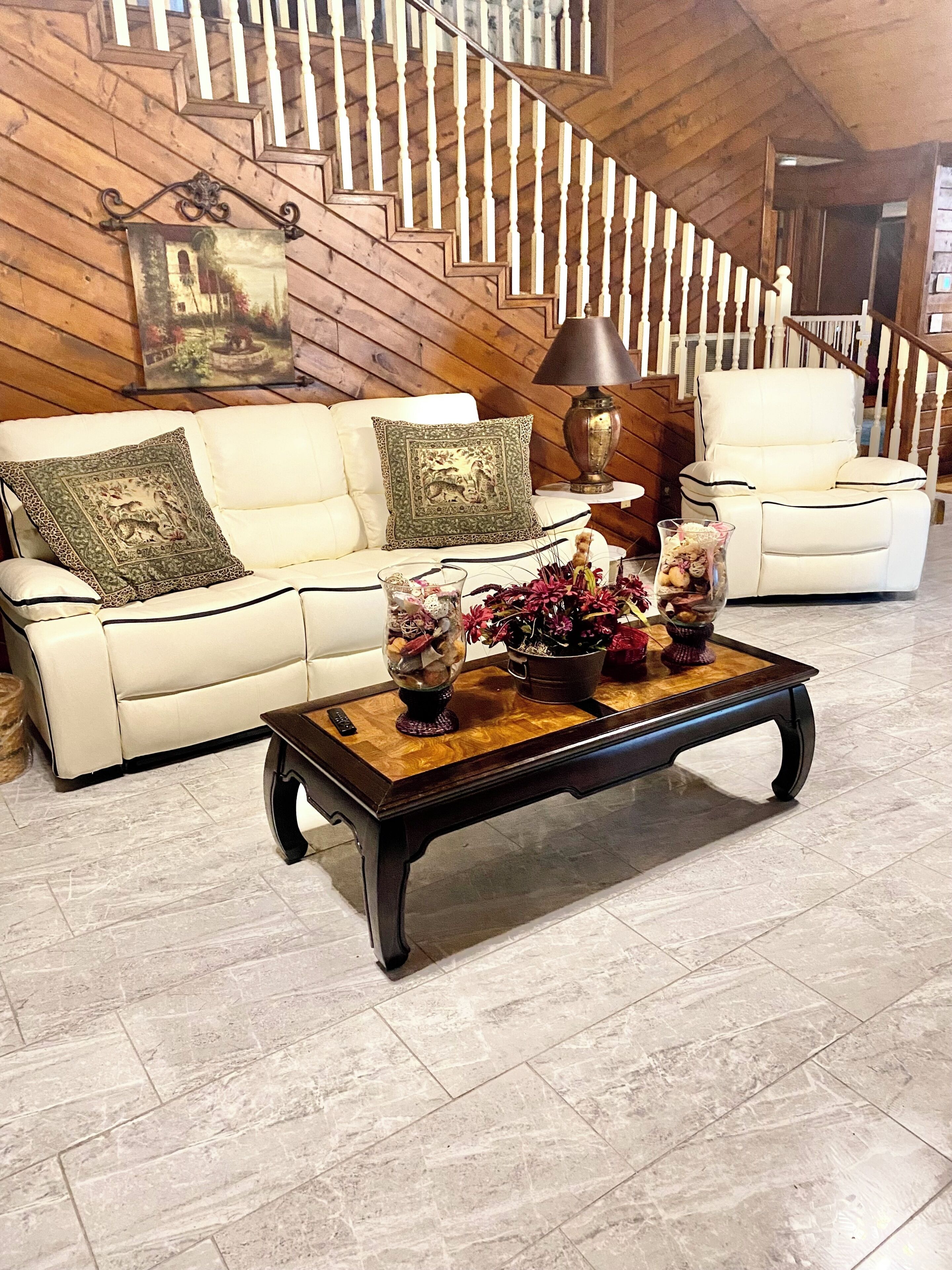 Un salón con un sofá blanco, una mesa de centro de madera y una escalera con barandillas de madera.