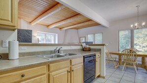 Una cocina con armarios de madera, lavavajillas, fregadero y un comedor con sillas.