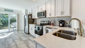 A modern kitchen with white cabinets, a stainless steel sink, a microwave, and a dishwasher. - Fernandina Beach Paradise: Steps to Shore! (Fernandina Beach)