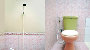 Un baño con inodoro, cabezal de ducha y baldosas estampadas de color rosa.