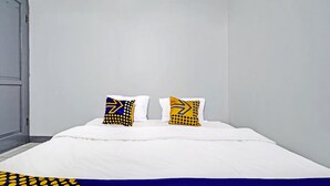 Una cama con ropa de cama blanca y dos almohadas de diseños geométricos.