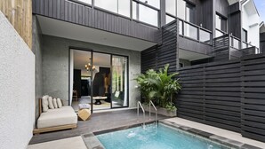 Un área de piscina moderna al aire libre, con una zona de estar integrada y un ventanal corredizo que da a un espacio habitable.