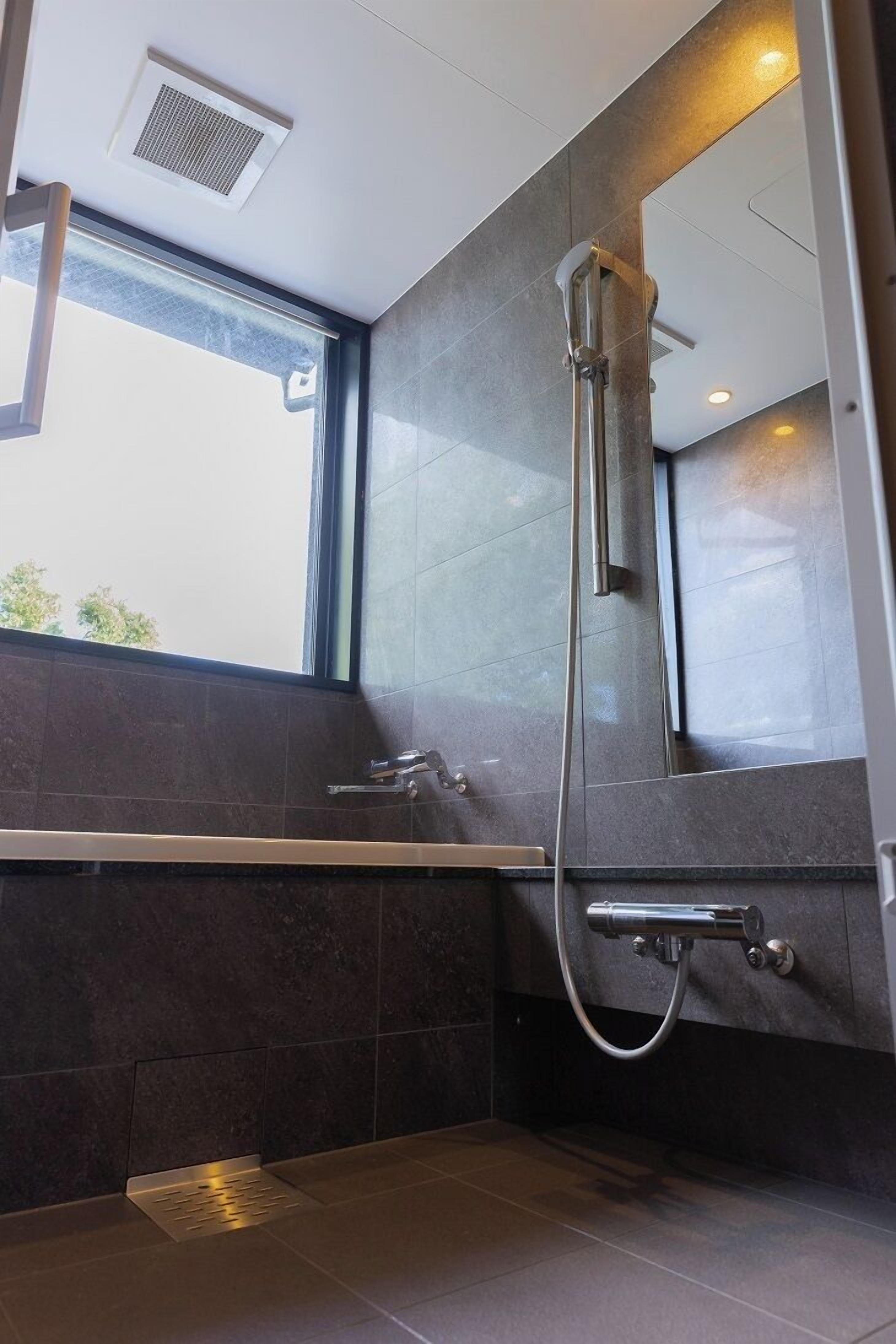A modern bathroom with a large mirror, a bathtub, and a shower.