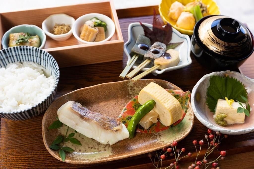 Una comida tradicional japonesa con arroz, pescado y diferentes guarniciones.