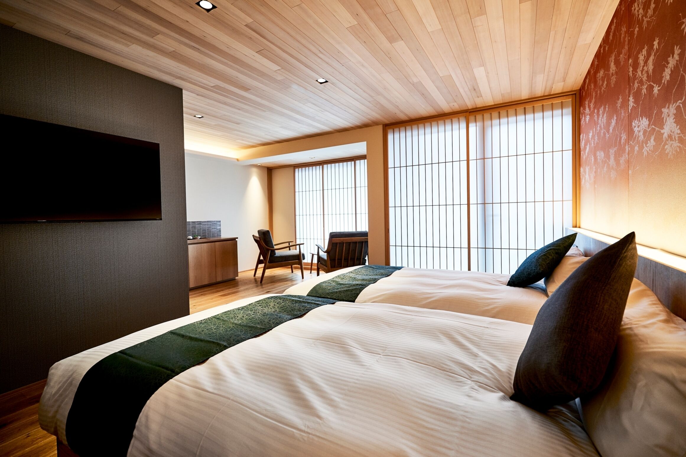 A hotel room with two beds, a desk, and a chair.