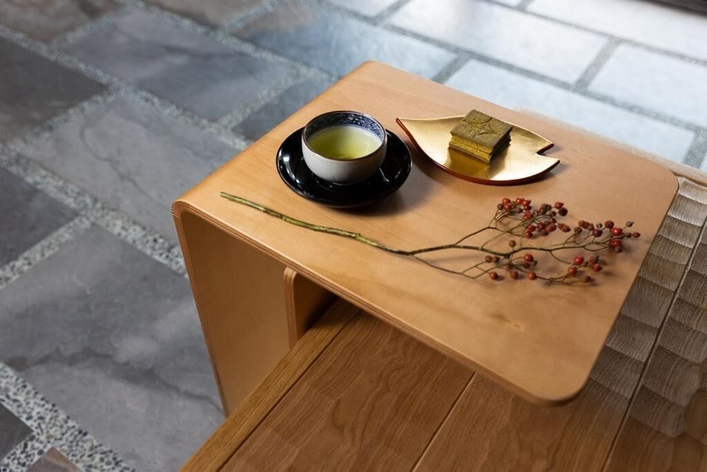 A small wooden table with a cup of tea, a piece of cake, and dried flowers.