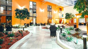 A spacious indoor atrium with a central fountain, surrounded by seating areas and potted plants.