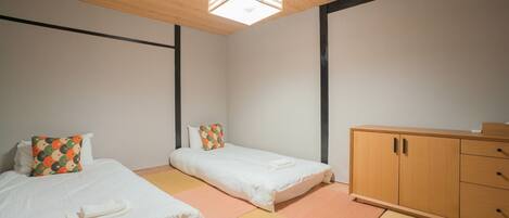 A room with two beds, a wooden cabinet, and a ceiling light fixture.
