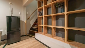 A modern kitchen with a black refrigerator, wooden shelving unit, and a clock on the wall. - Kujo Seisen (Kyoto)