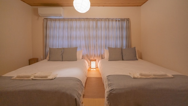 A hotel room with two beds, a ceiling fan, an air conditioning unit, and a nightlight. - Kujo Seisen (Kyoto)