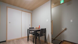 A room with a wooden floor, a table with chairs, a door, and a broom leaning against the wall. - Kujo Seisen (Kyoto)