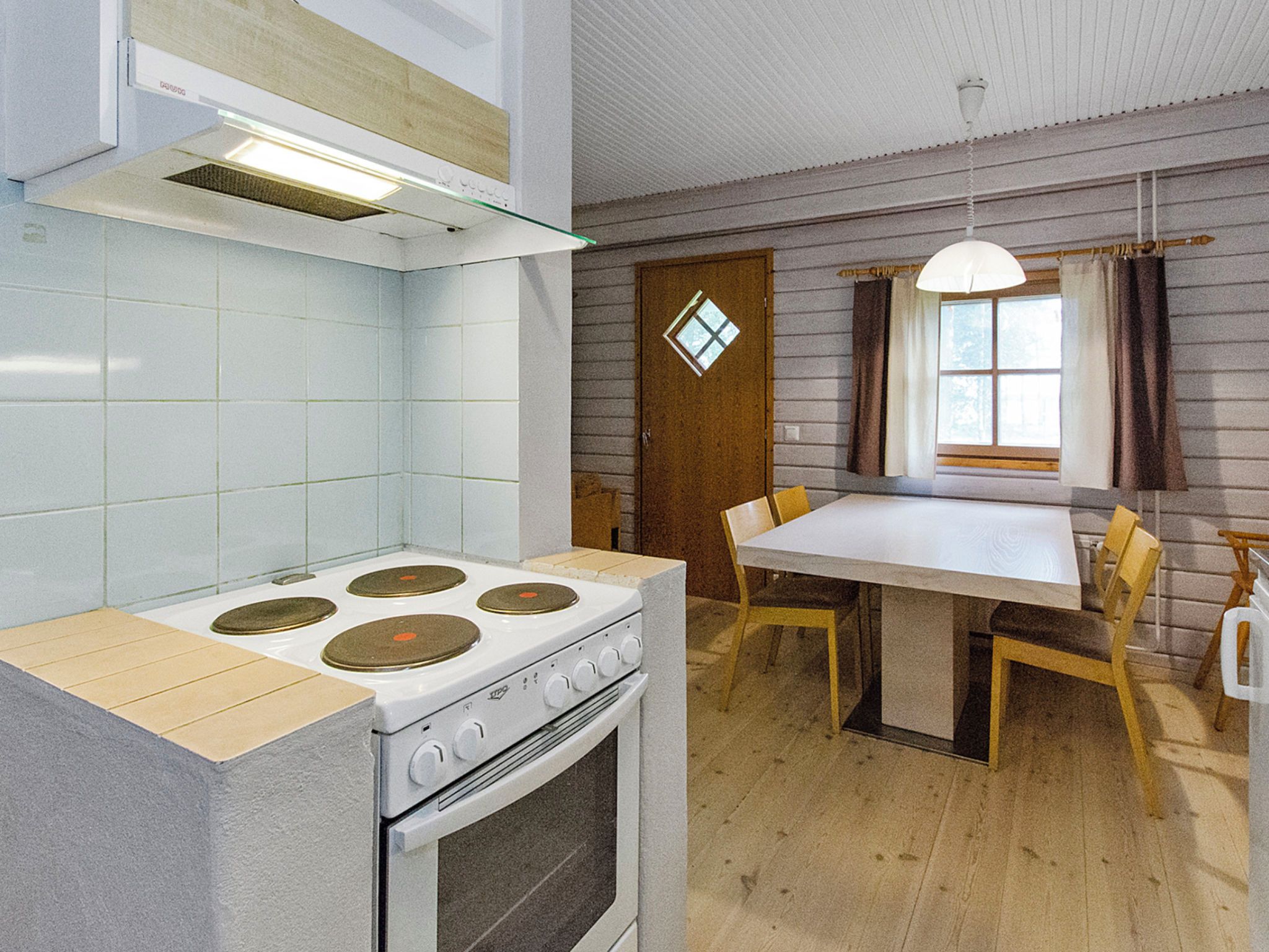 A compact kitchen with a stove, a dining table, and chairs.