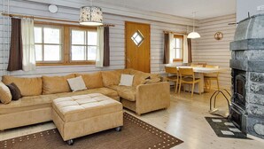 Una sala de estar acogedora con un sofá modular, una chimenea y un comedor con una mesa y sillas.