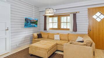 A room with a sectional sofa, a rug, a painting, and a window with curtains.