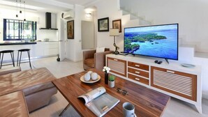 Una sala moderna con un televisor de pantalla plana grande, una mesa de centro de madera y un sofá.