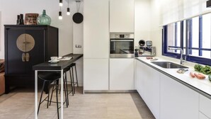 Una cocina moderna con armarios blancos, encimera negra y horno empotrado.