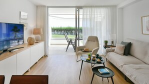 A modern living room with a flat-screen TV, a sofa, a coffee table, and a dining area with a chair. - Beachfront Nasas 4 JM by Interhome (San Agustín)
