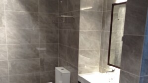 Un baño moderno con baldosas grises, un inodoro blanco y un lavabo con espejo.