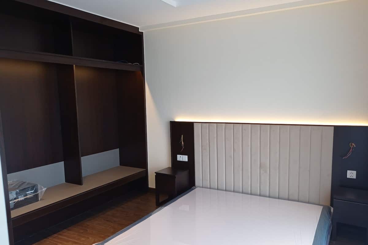 A modern bedroom with a large bed, built-in shelving, and a bedside table.
