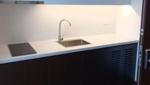 Una cocina moderna con armarios blancos, un lavamanos de acero inoxidable y una encimera negra.