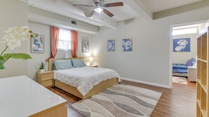 Een slaapkamer met een bed, nachtkastjes, een plafondventilator en kunstwerken aan de wanden.