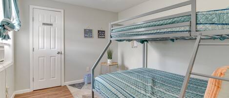Une chambre avec des lits superposés, un ventilateur de plafond, une porte portant l’inscription « Réservé au personnel » et une petite plante posée sur une table d’appoint.