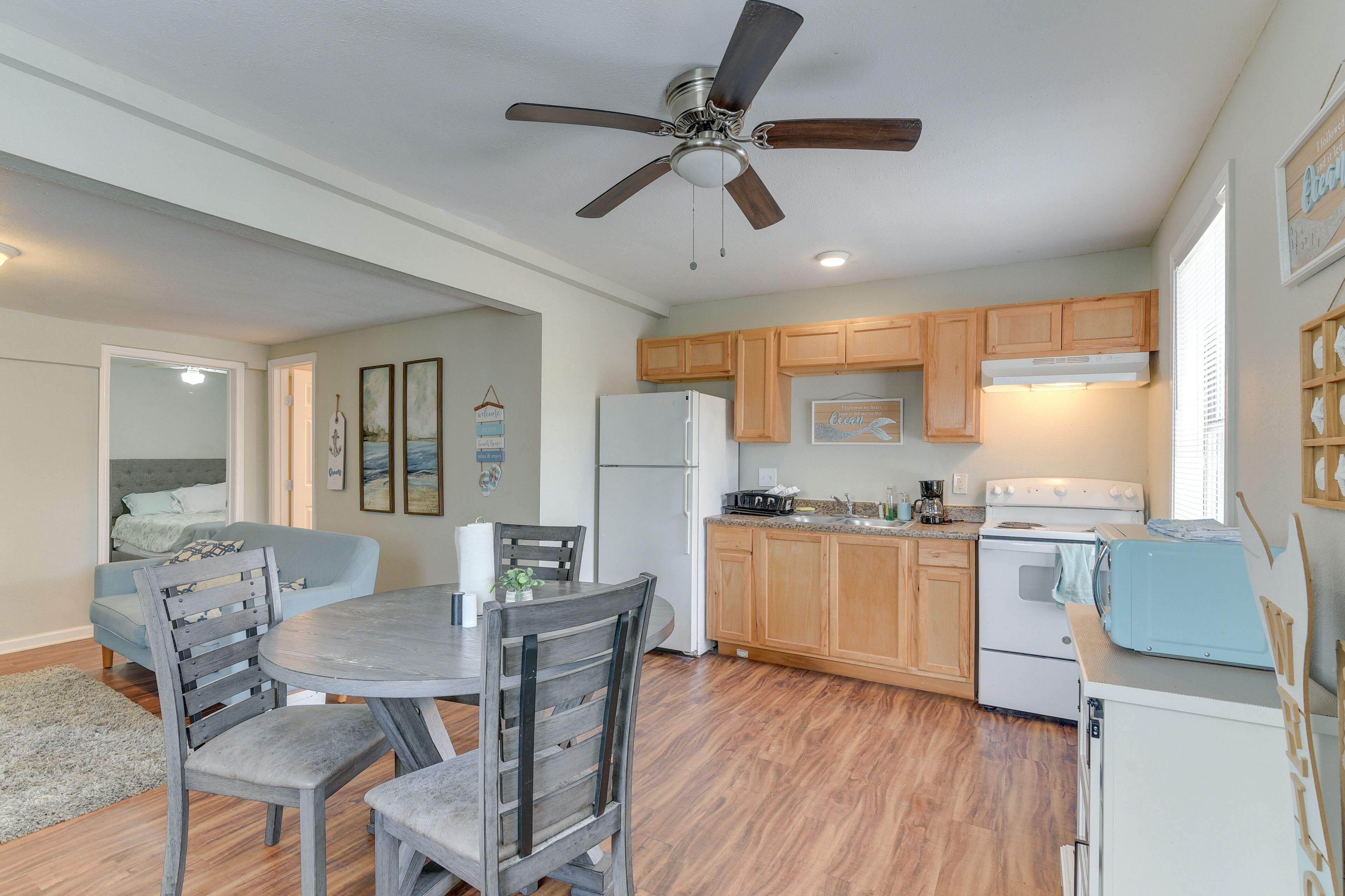 A compact kitchen with wooden cabinets, a built-in oven, and a ceiling fan.