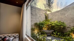 Ein modernes Wohnzimmer mit einem großen Fenster, einem grauen Sofa und einem kleinen Holztisch.