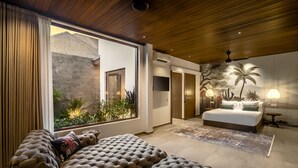 Ein modernes Schlafzimmer mit einem großen Bett, einer Couch und Gartenblick durch eine Schiebetür.