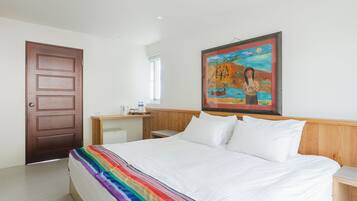 Une chambre d’hôtel avec un lit, une tête de lit en bois, une table de chevet, un tableau au mur et une porte.