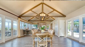 Un vaste espace dédié à la salle à manger, avec une grande table en bois, des chaises confortables et un lustre.